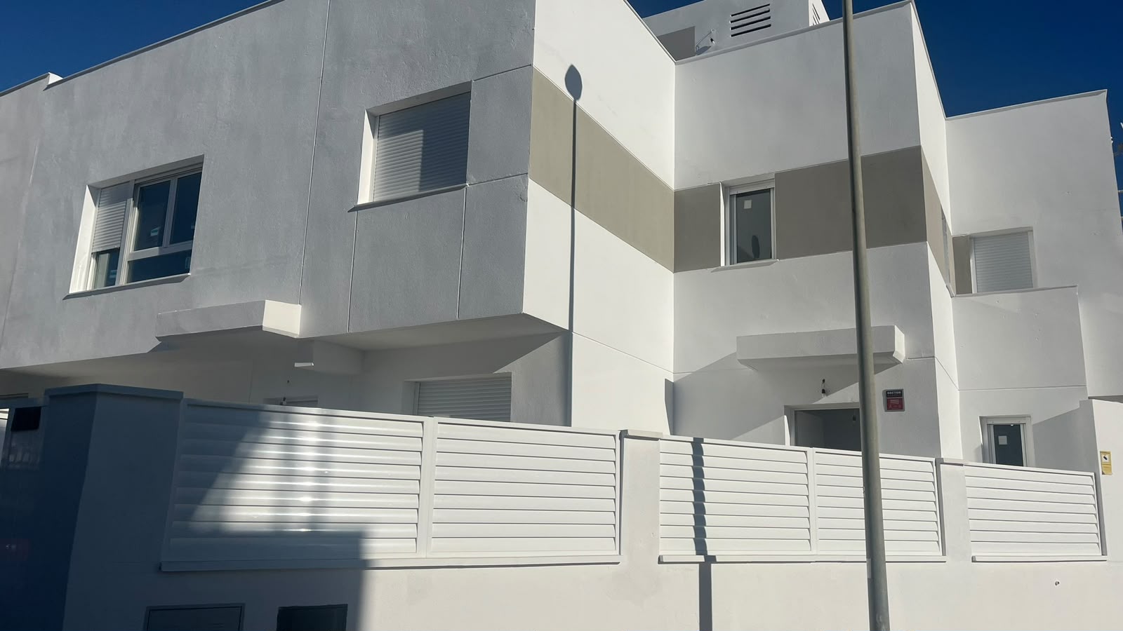 Vallado exterior pintado de blanco a lo largo de la calle